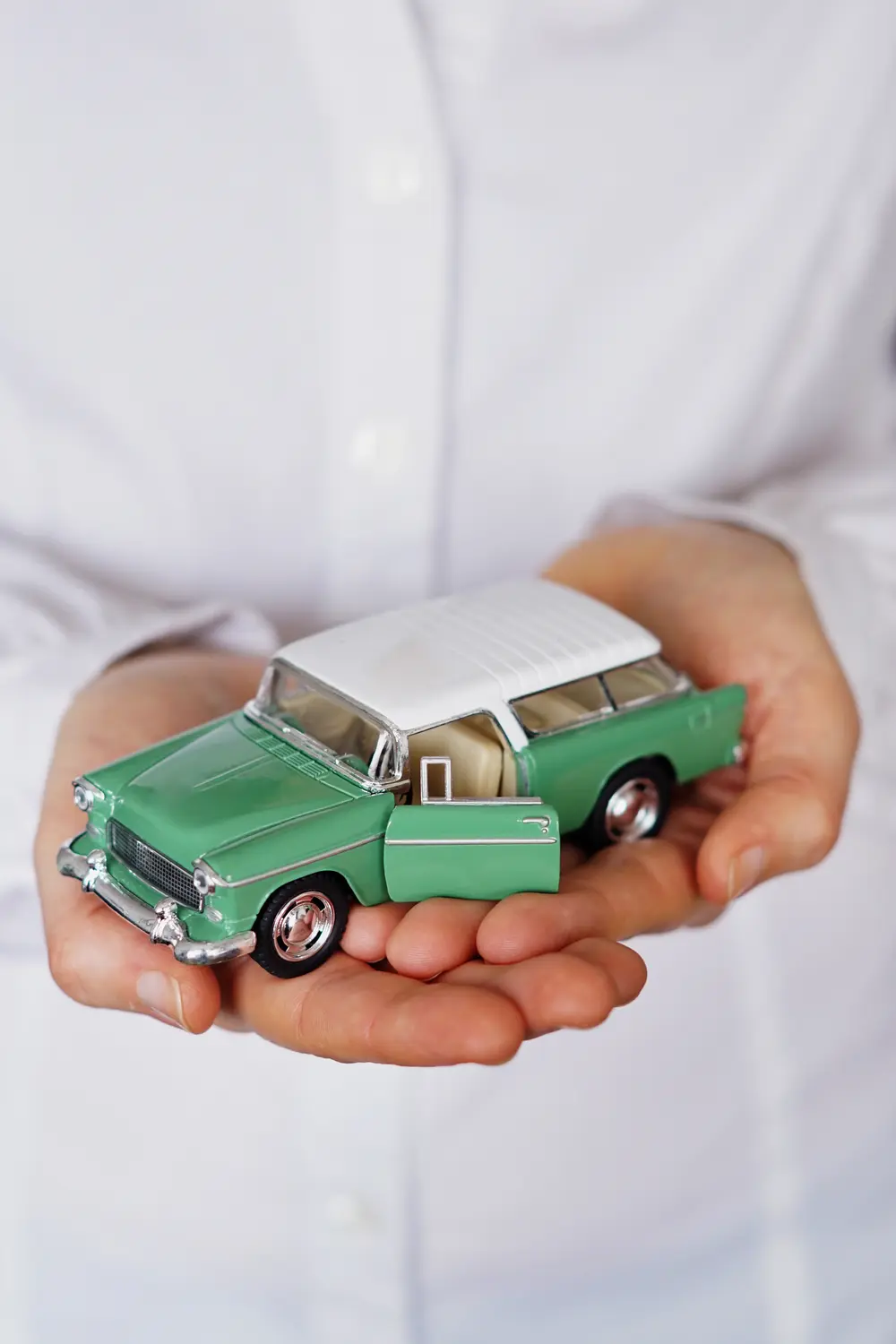 Manos sosteniendo con cuidado un auto de juguete verde