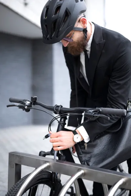 Ciclista con casco asegurando su bicicleta a un soporte
