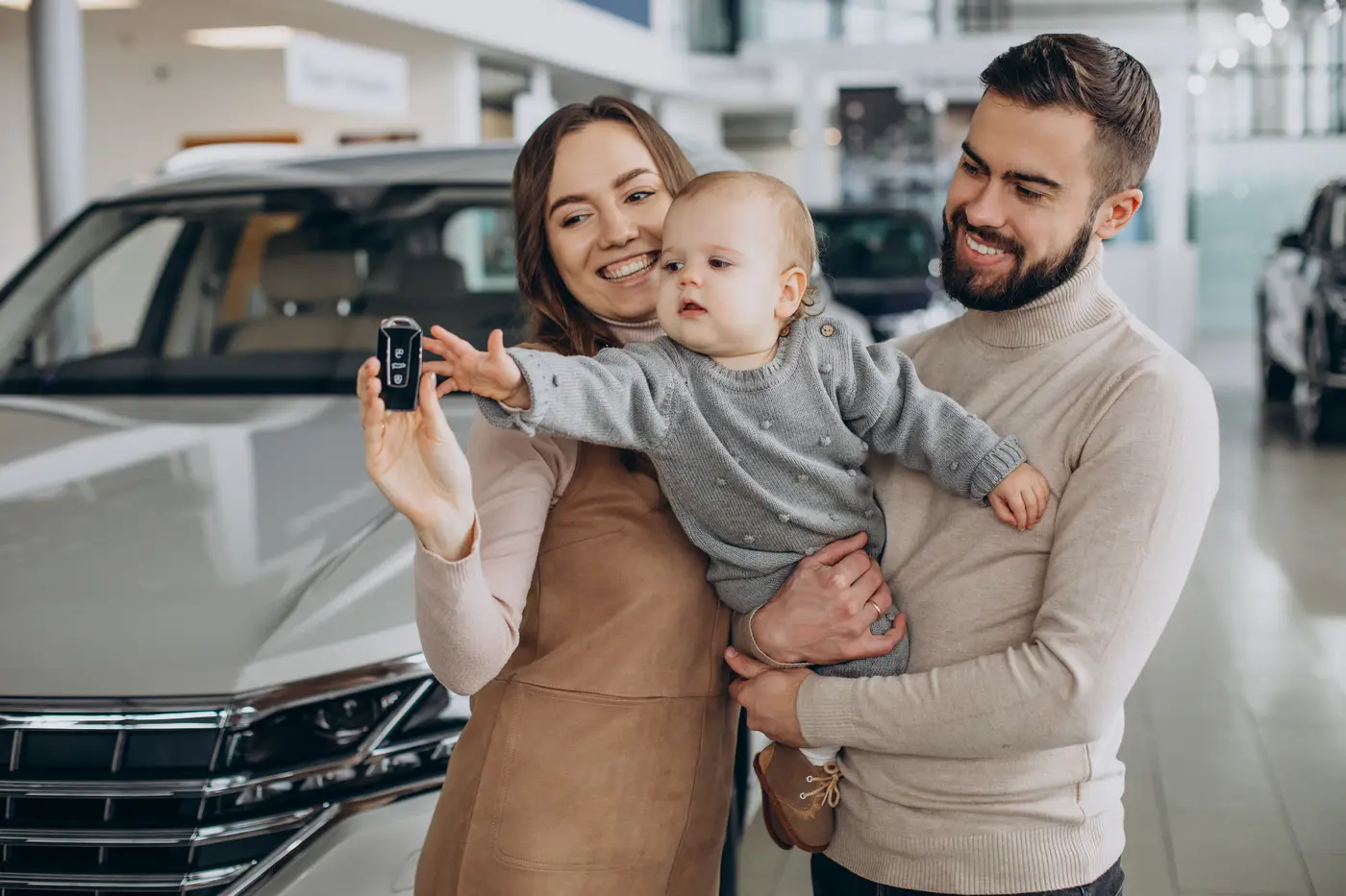 Familia con su bebé eligiendo un auto y mostrando las llaves