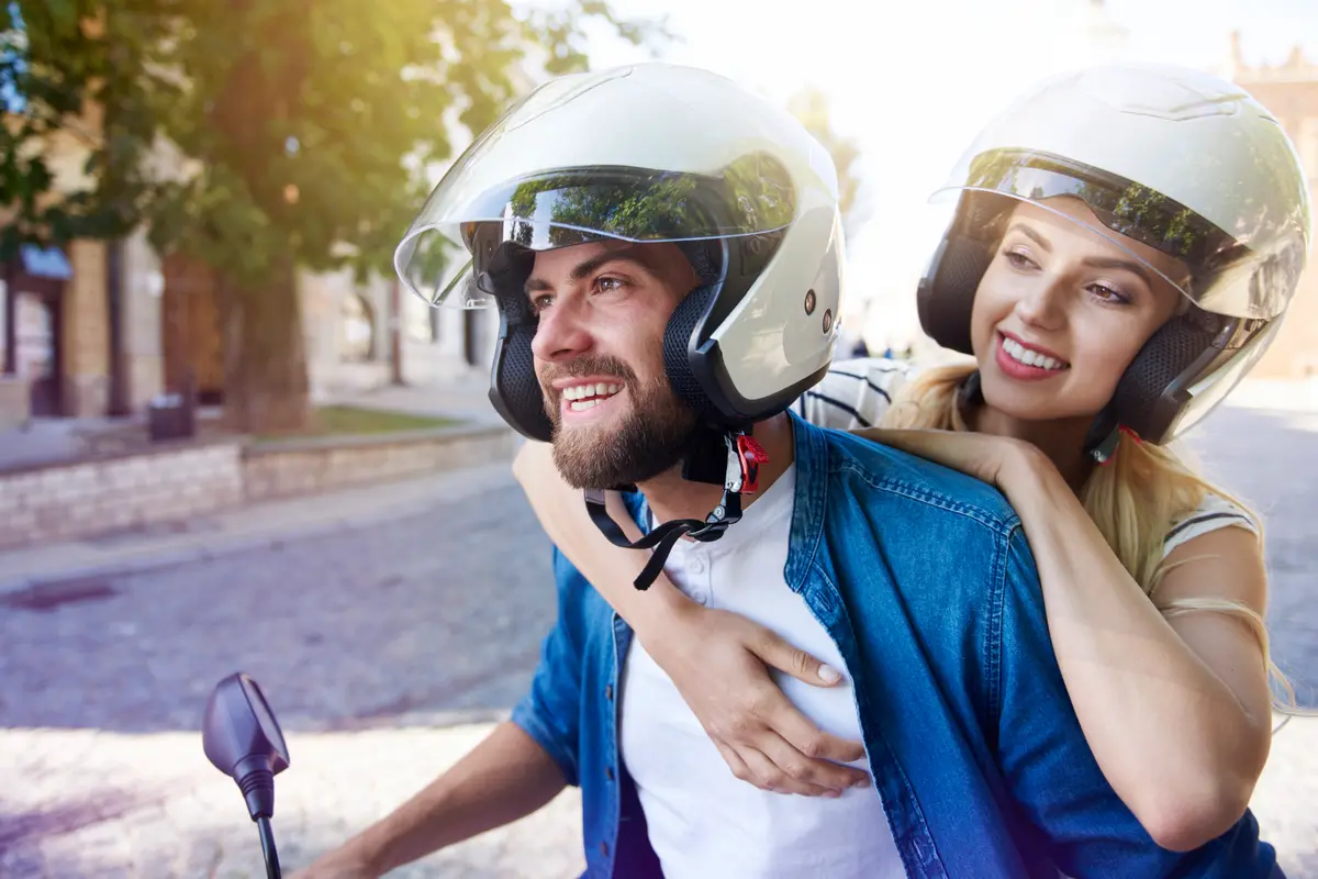 Pareja con cascos viajando en moto por la ciudad